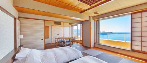 Una habitación con dos camas, una mesa de comedor y vista al mar.