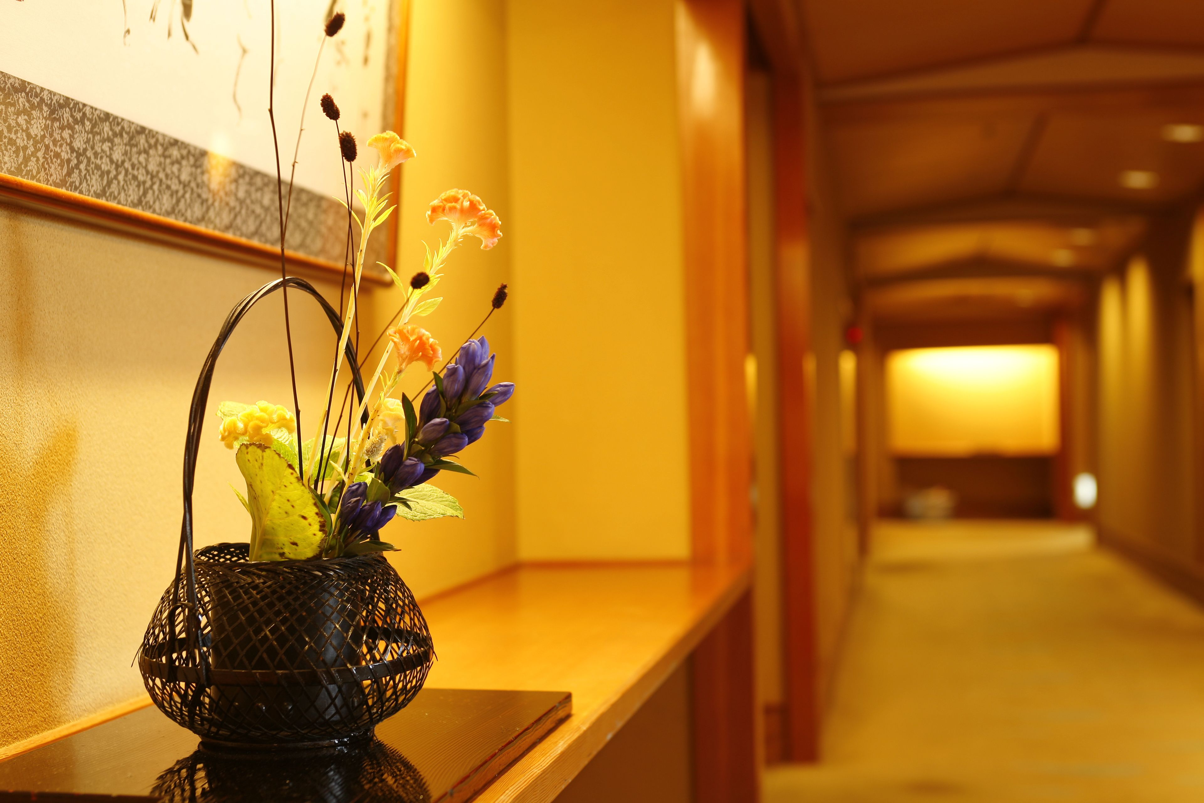 A hallway with a decorative vase of flowers on a wooden bench.