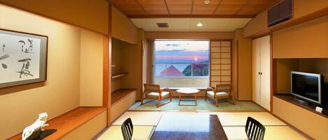 A traditional Japanese-style room with tatami flooring, a low table, and a television.