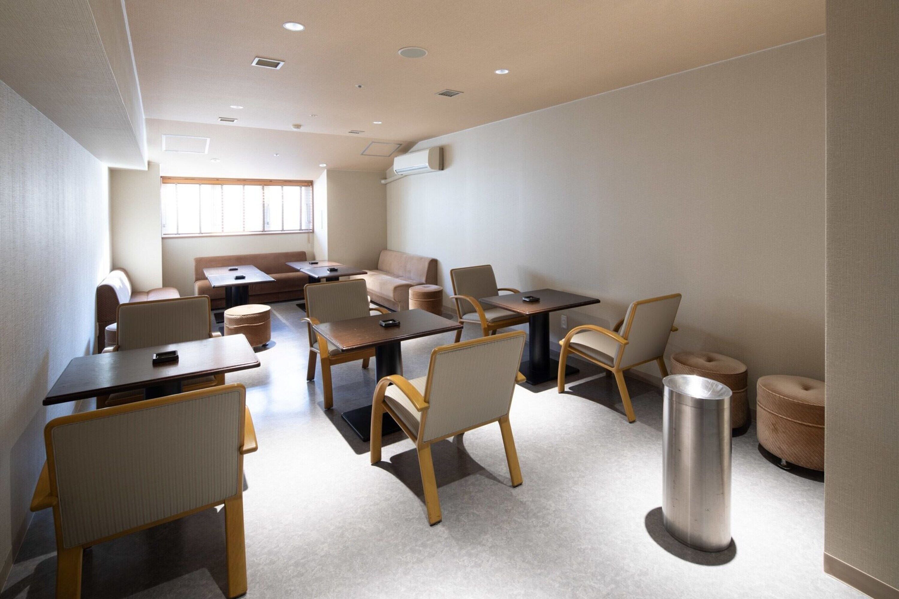 A modern meeting room with a long table, several chairs, a sofa, and a trash can.