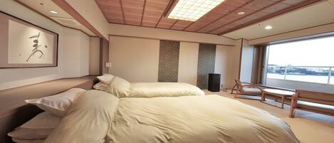 A modern hotel room with a large bed, a seating area with a view, and a large window.