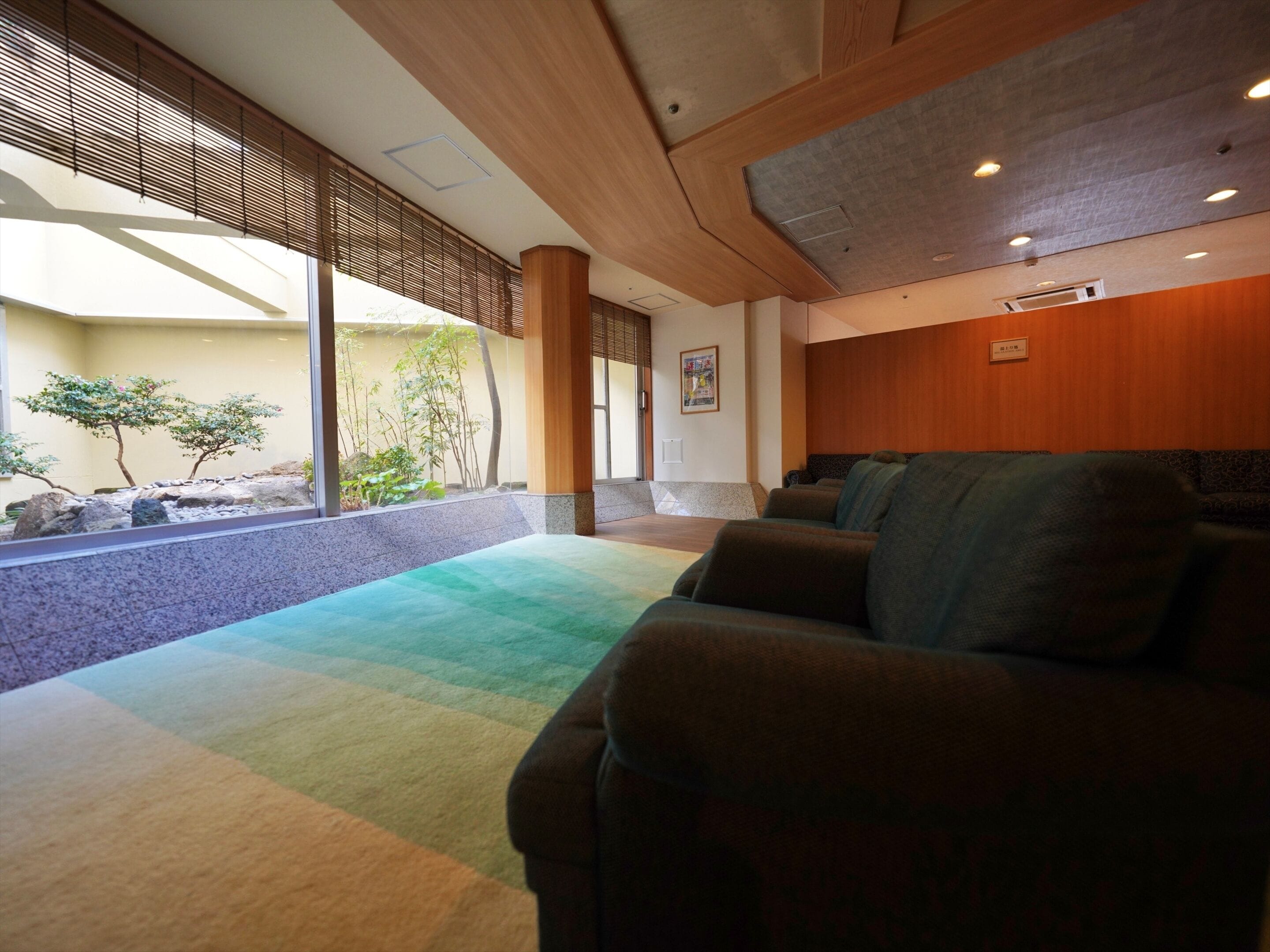 A modern interior with a seating area, large windows, and a view of a garden.