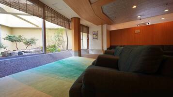 A modern interior with a seating area, large windows, and a view of a garden.