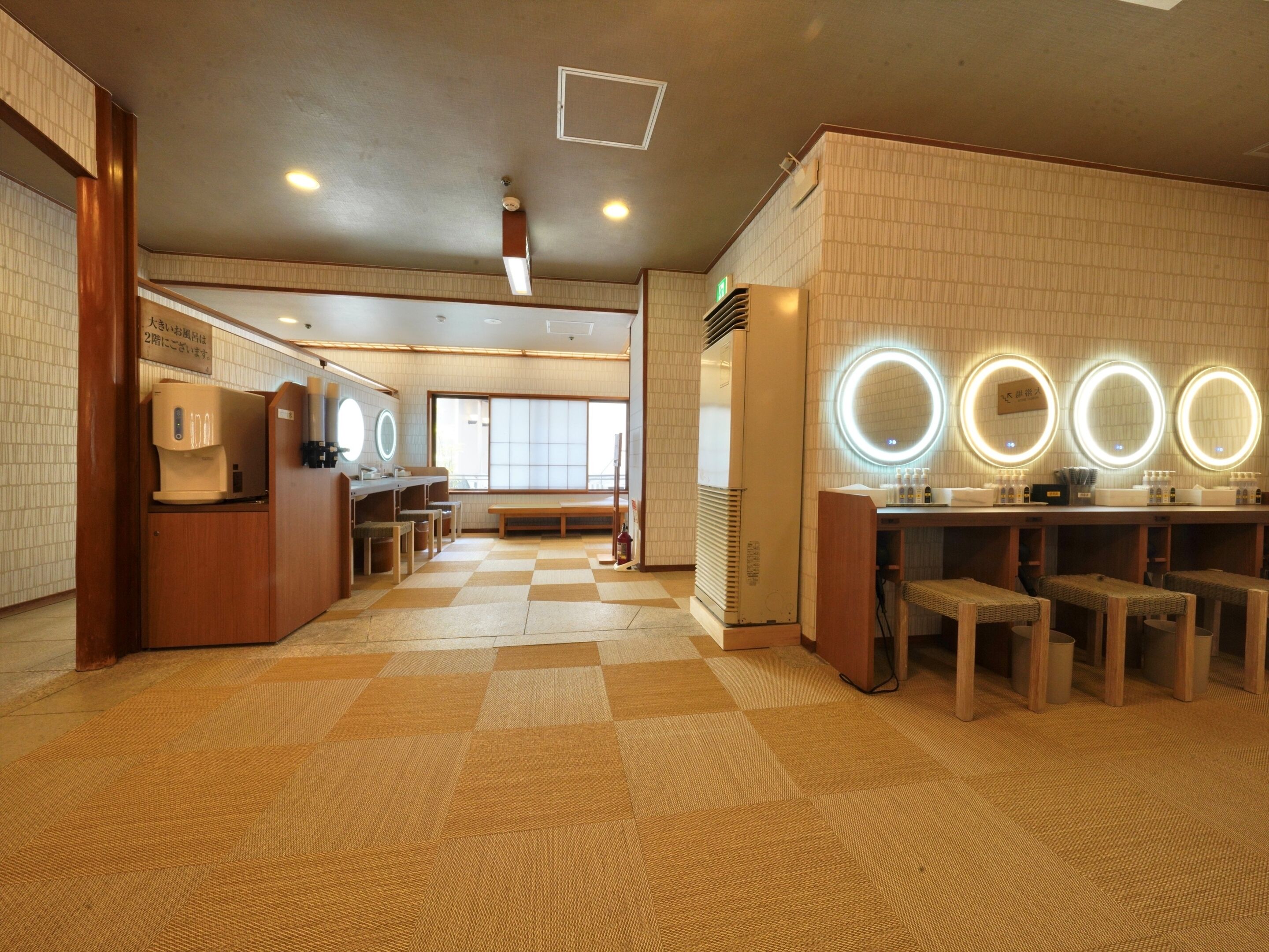 A hotel lobby with a checkered floor, wooden furniture, a reception desk, and a large window.