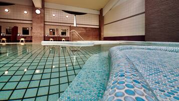 An indoor swimming pool with a tiled floor and a blue patterned edge.