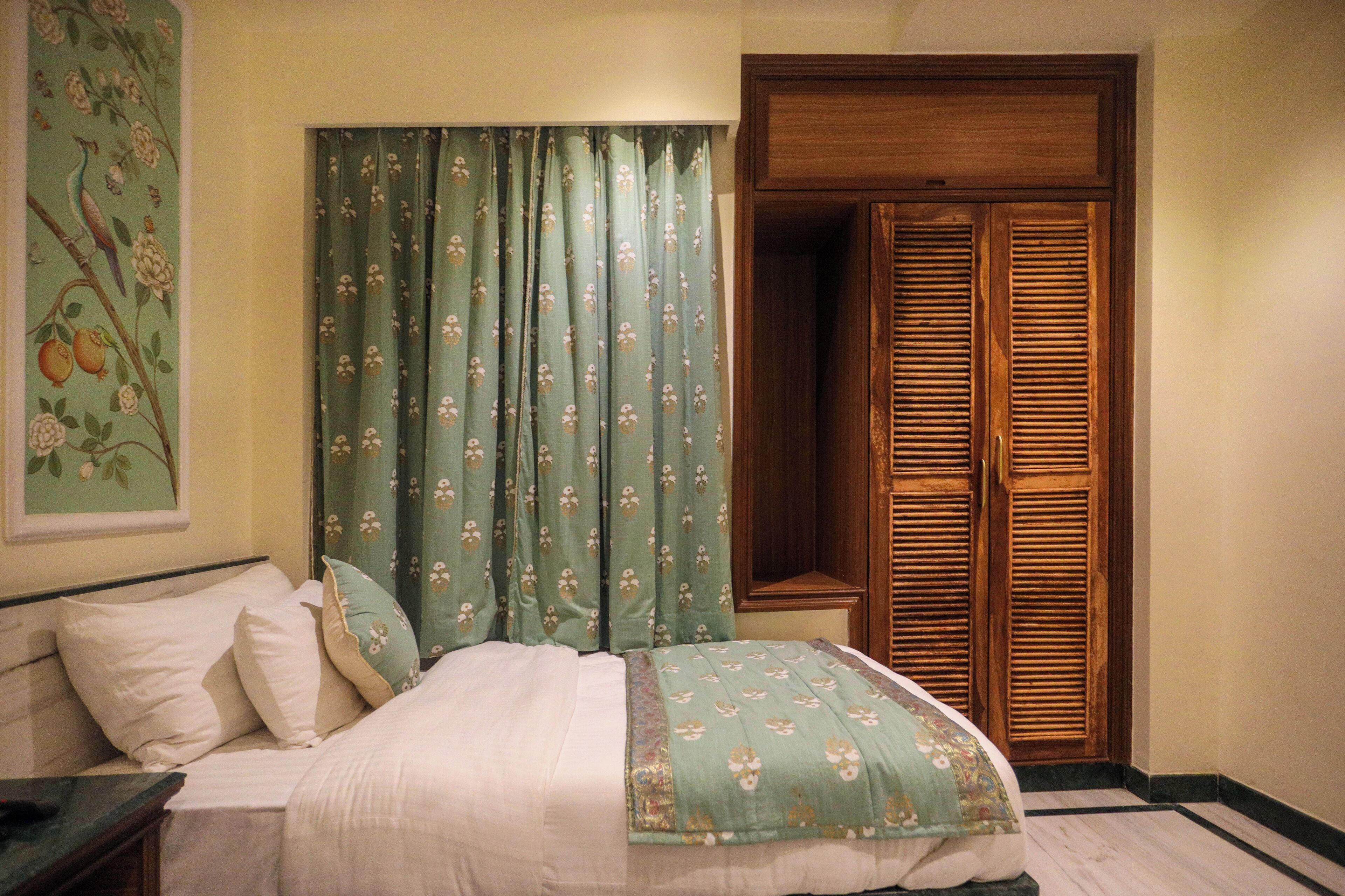 Une chambre à coucher avec un lit, des rideaux, une armoire en bois et un tableau mural.