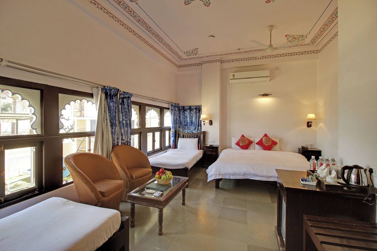 Une chambre d’hôtel avec deux lits, un coin salon avec une table basse et une vue par la fenêtre.