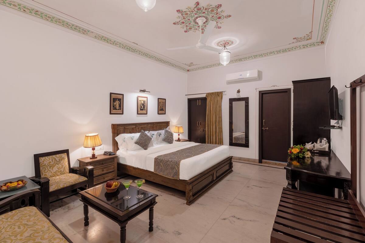 Une chambre d’hôtel équipée d’un lit, d’un bureau, d’une chaise, d’une armoire et d’un ventilateur de plafond.