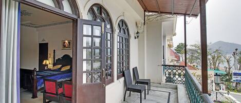 Une chambre avec un lit, une chaise et un balcon donnant sur la ville.
