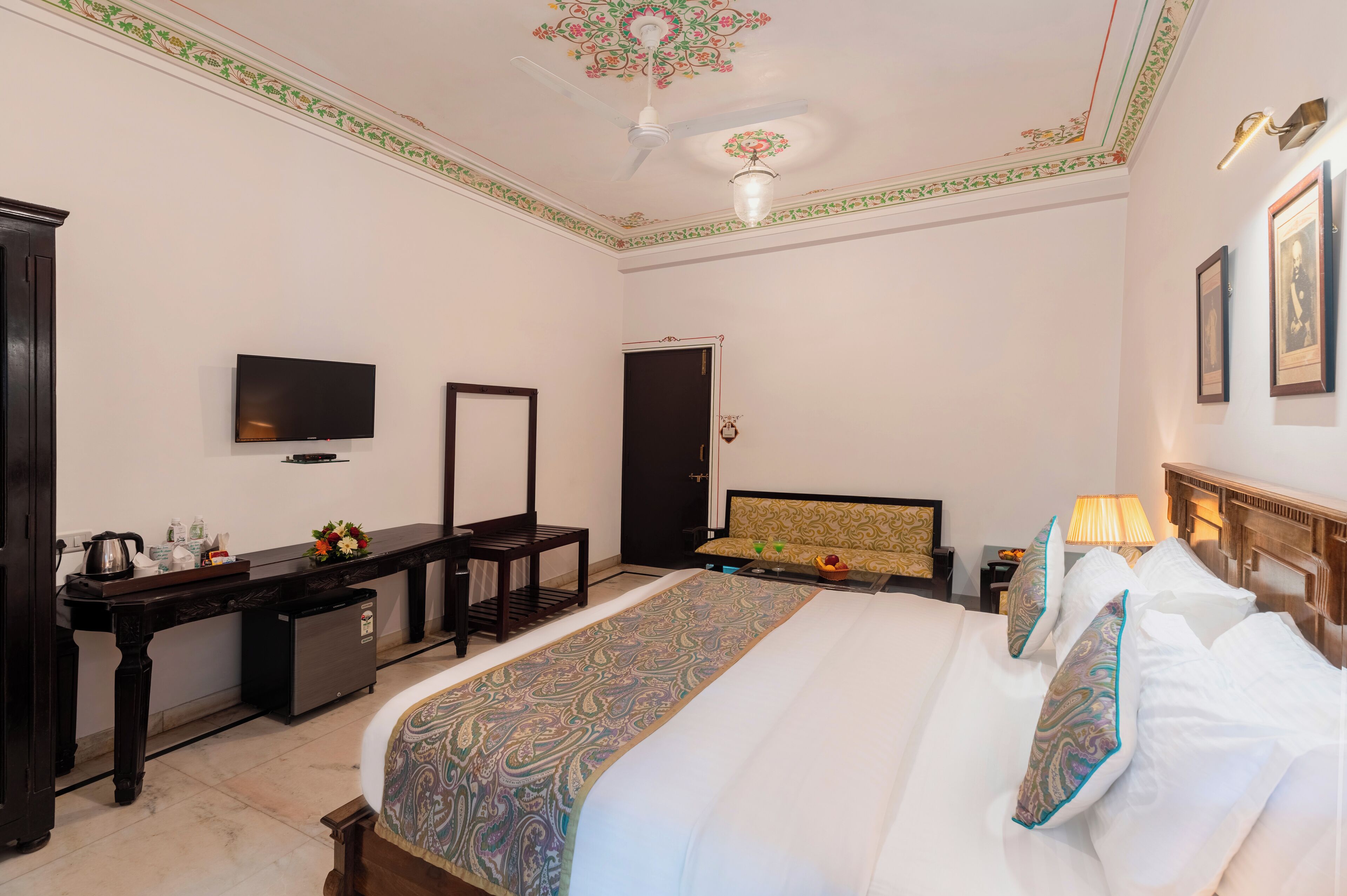 A hotel room with a bed, a desk, a television, a wardrobe, and a door.