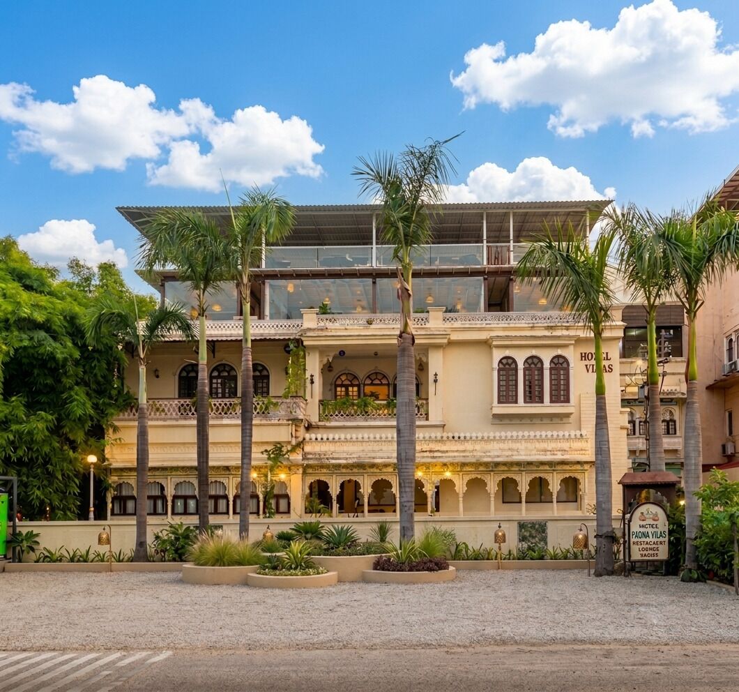 Un hôtel de style architectural traditionnel, doté de nombreux balcons et d’une cour intérieure agrémentée de palmiers.