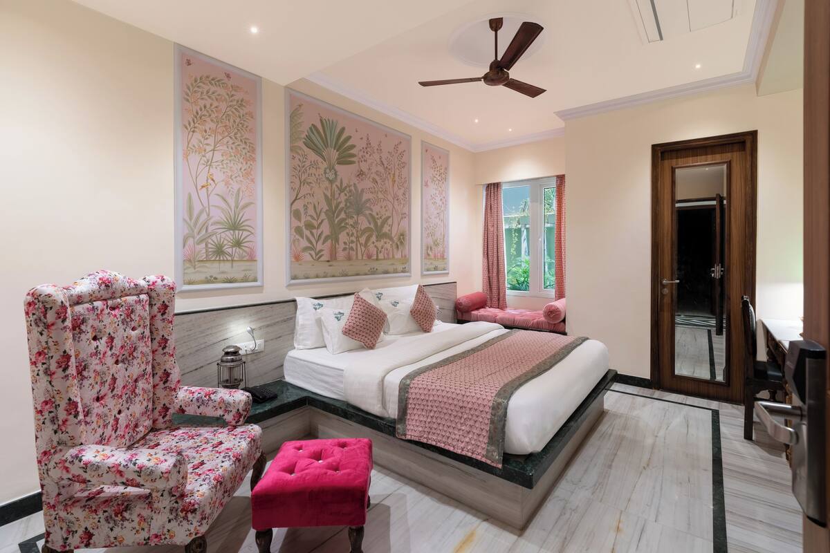 Une chambre à coucher avec un lit, une chaise, une petite table et un ventilateur de plafond.