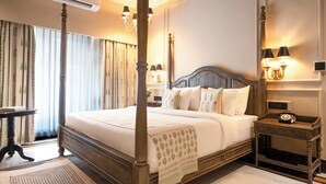 A four-poster bed with a wooden headboard, a bedside table with a lamp, and a nightstand with a telephone. - Panna Vilas - A Lake Facing Boutique Hotel (Udaipur)