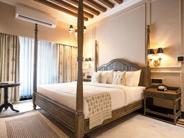 Una cama con dosel y tablero de madera, una mesita de noche con lámpara y un atril con teléfono.