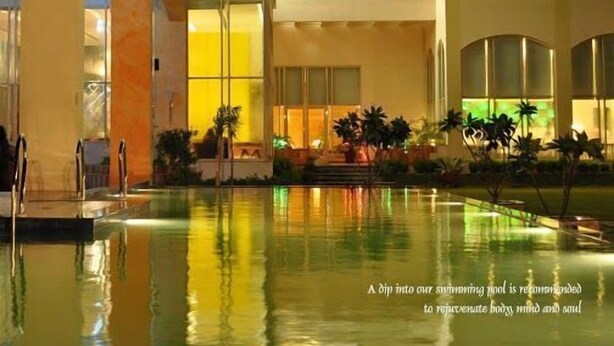 Un hotel con zona de piscina, varios pisos y un interior bien iluminado.