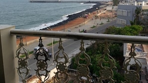 Blick auf die Küste vom Balkon mit Metallgeländer, ein Strand und ein Pier in der Ferne.