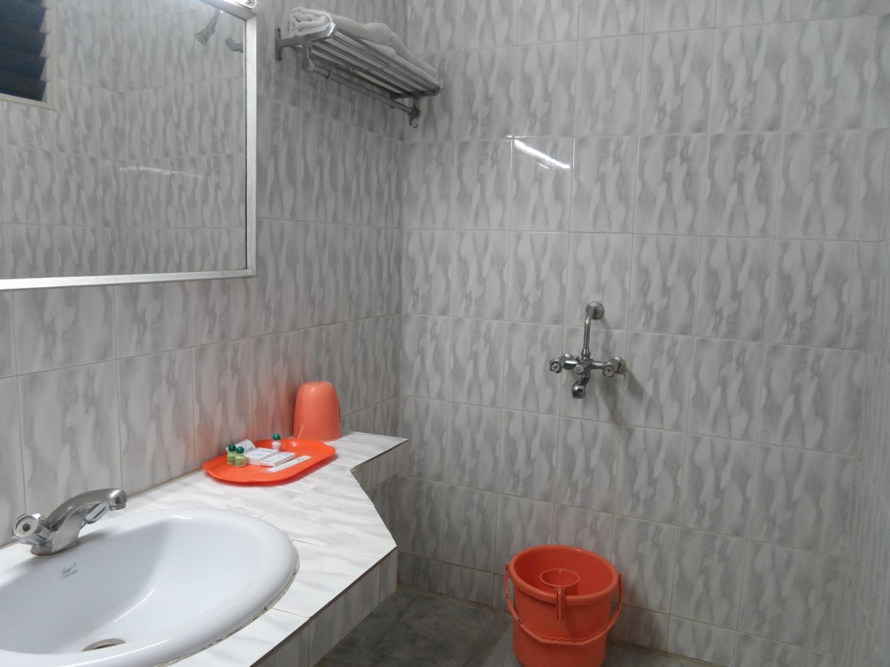 A bathroom with a white sink, a mirror, a towel rack, and a shower.