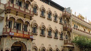 Um edifício de vários andares com uma placa indicando 'Hotel Ruby', identificando-o como um hotel. Possui várias varandas com designs elaborados, e o edifício apresenta um estilo arquitetônico tradicional.