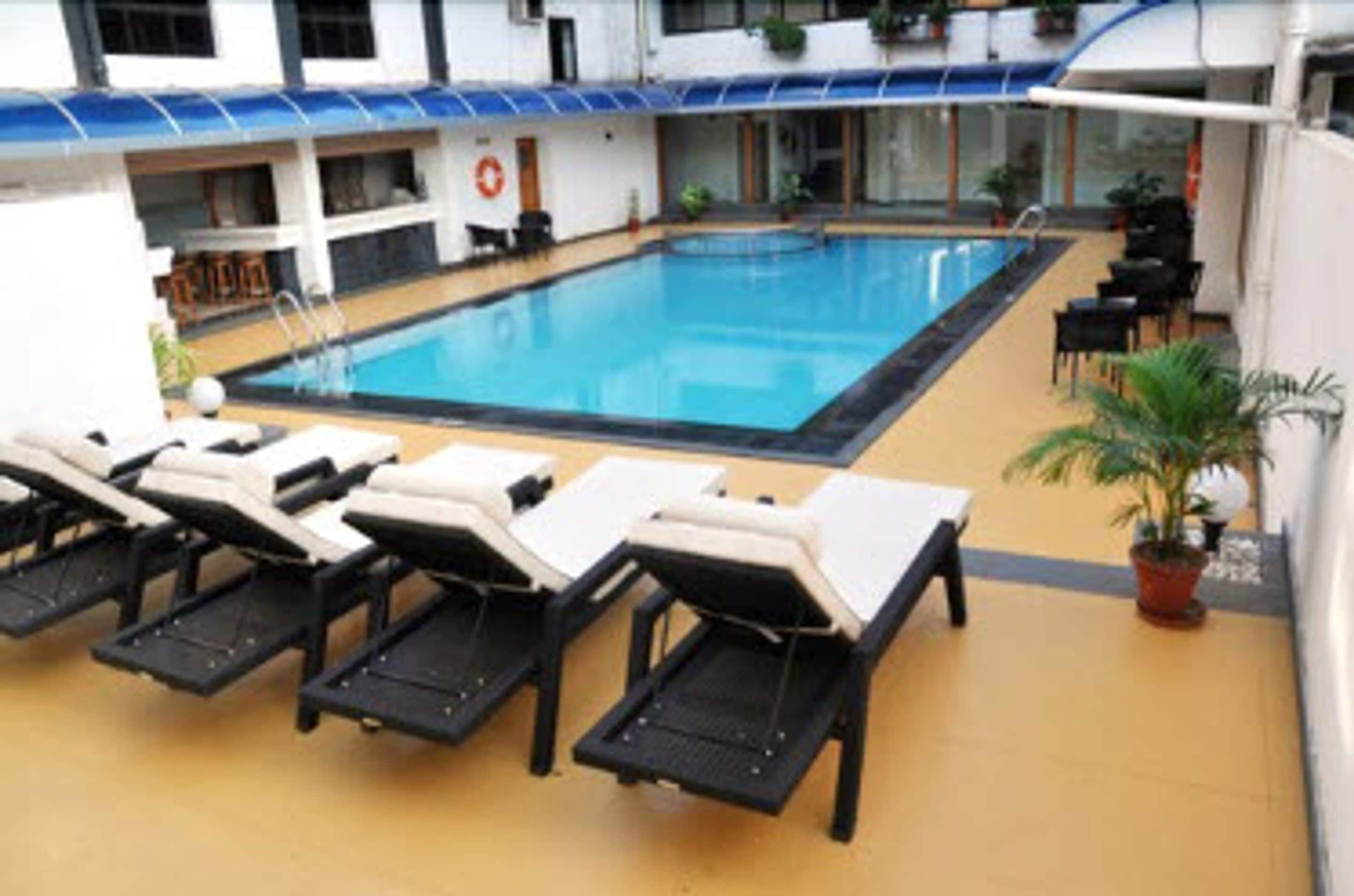Un espace piscine avec des chaises longues et une plante en pot.