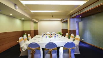 A conference room with a long table, chairs with sashes, and a blue carpet.