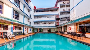 A swimming pool with lounge chairs and a lifebuoy on the wall.