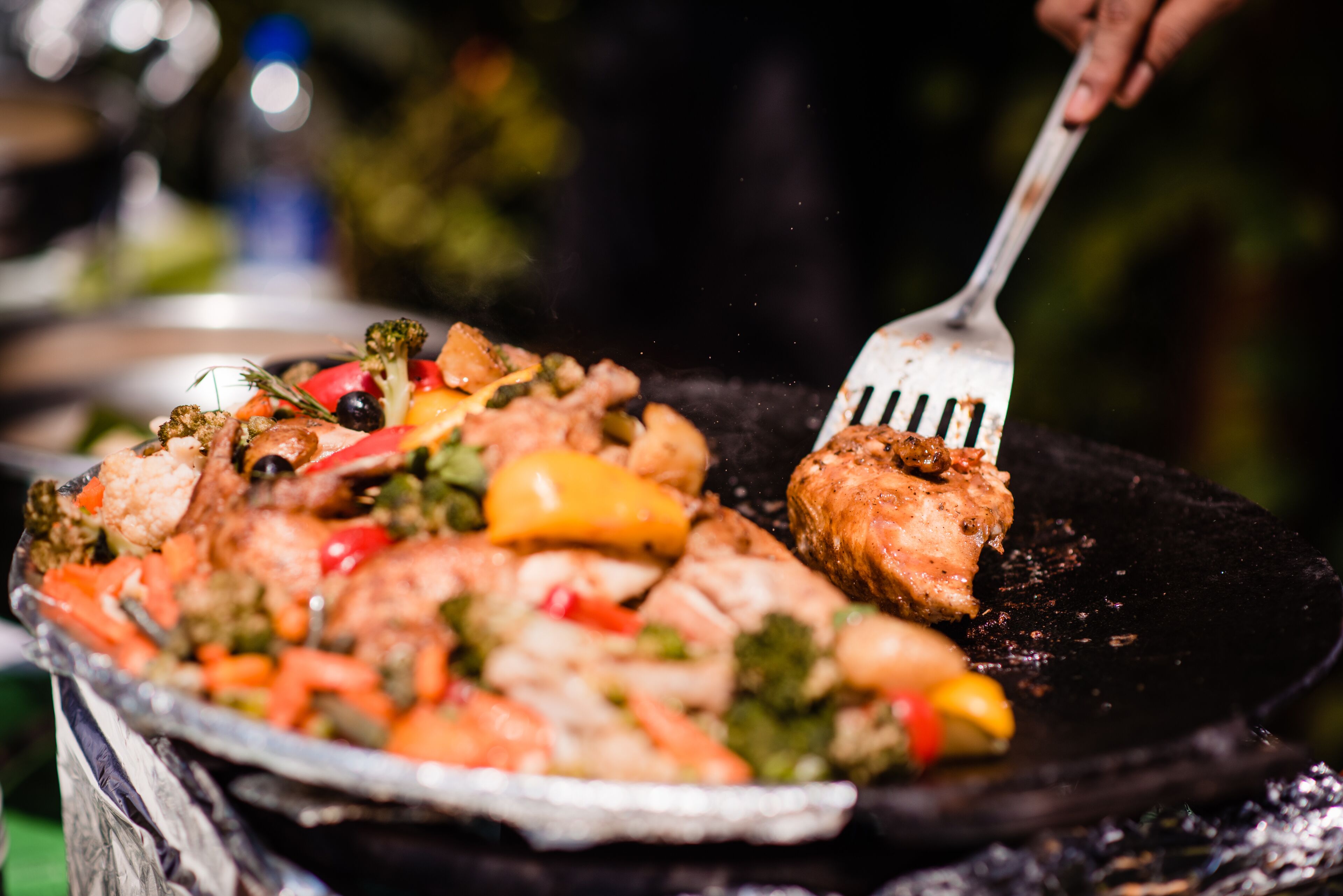 Ein Grill mit verschiedenen Gemüsesorten und einem Stück Fleisch, das darauf gebraten wird.