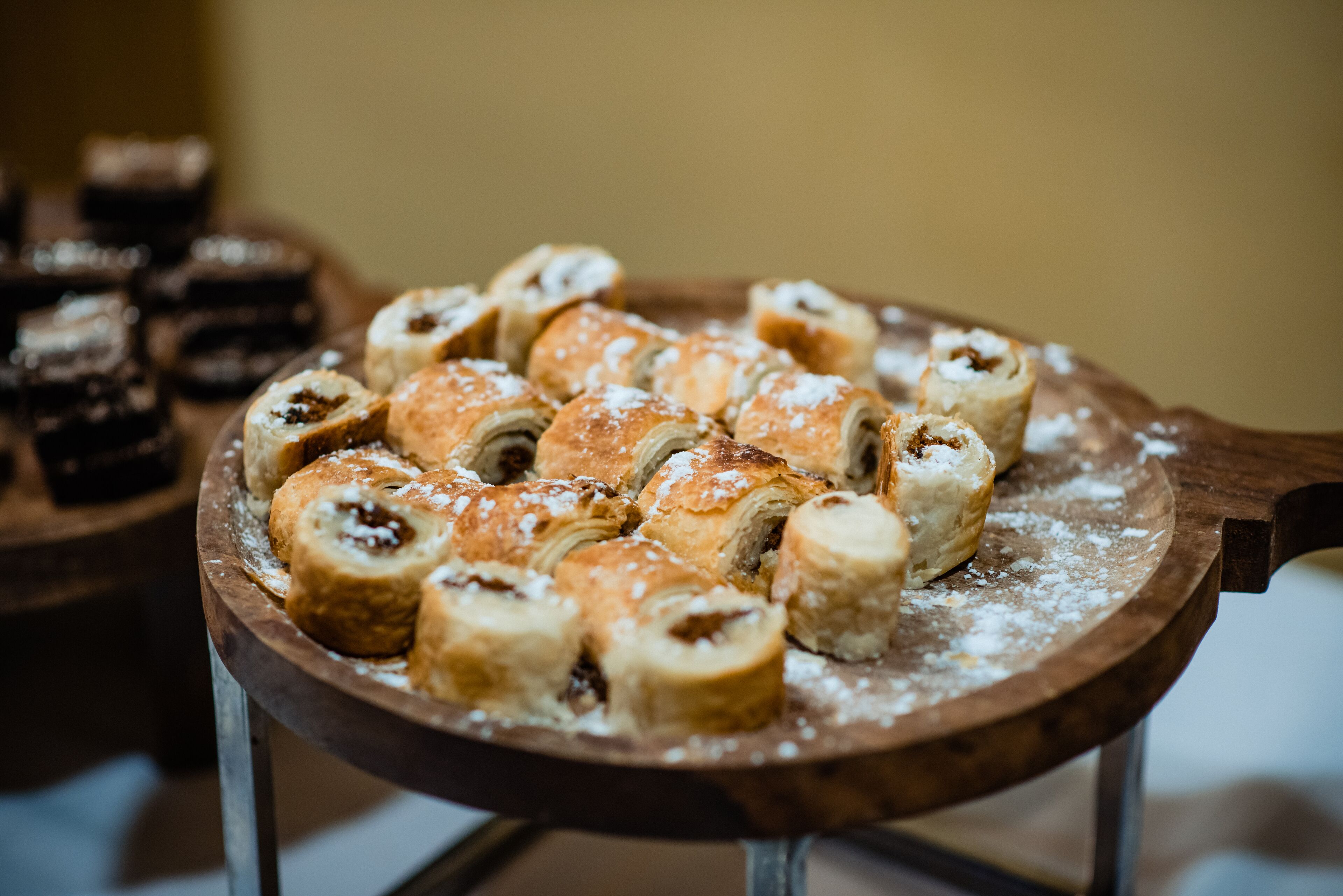 A wooden serving tray with pastries on a metal stand.