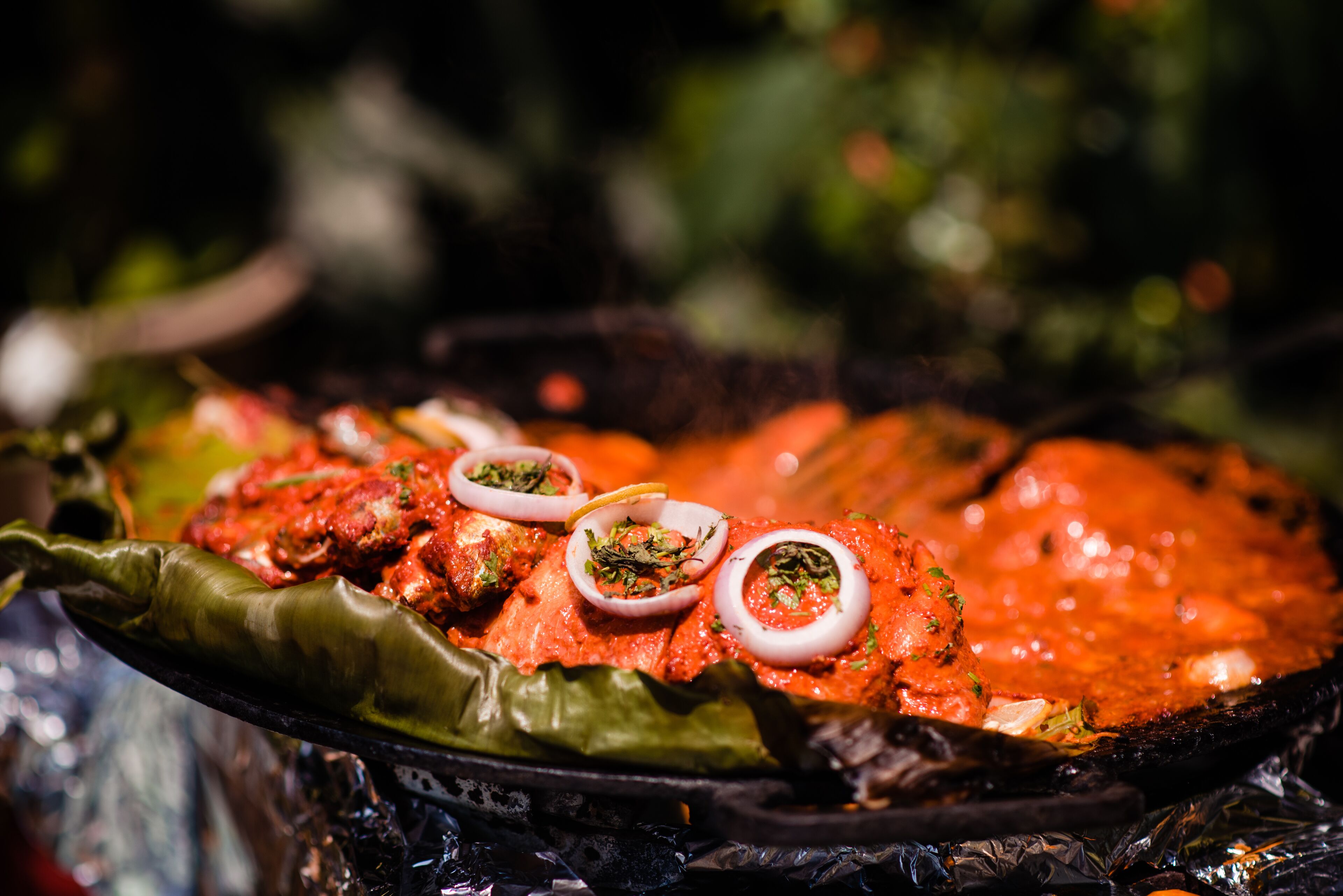 A large, shallow dish filled with a red, tomato-based dish garnished with slices of onion and herbs.