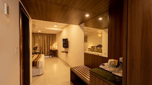 A hotel room with a wooden ceiling, a large mirror, a bedside table with a coffee maker, and a bed with a floral bedspread.