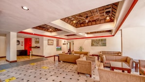 A spacious lobby with a high ceiling, checkered floor, and multiple seating areas.