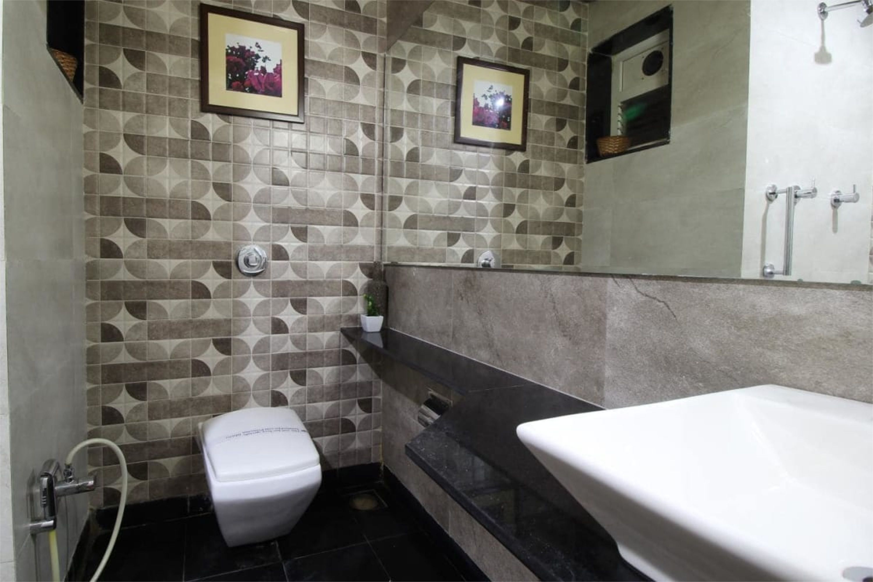 Ein Badezimmer mit Fliesenwand mit Muster, Toilette, Waschbecken und Spiegel.