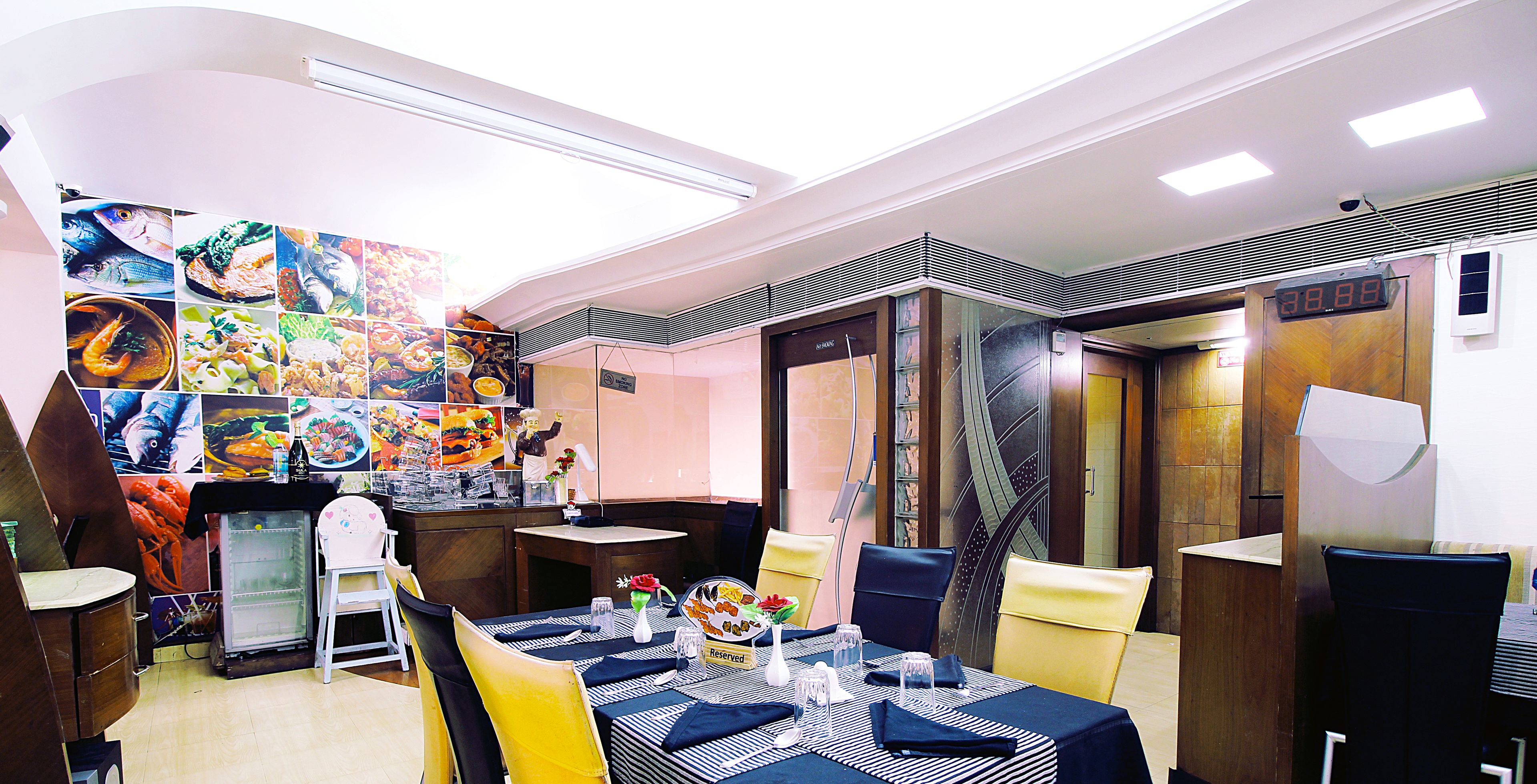 A restaurant with a dining area featuring a large menu board, a refrigerator, and a counter with a display of food items.