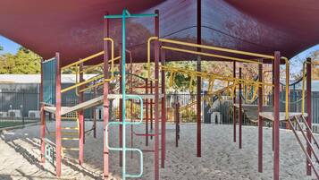 Kids can play and climb on the playground structure with a canopy overhead for shade.