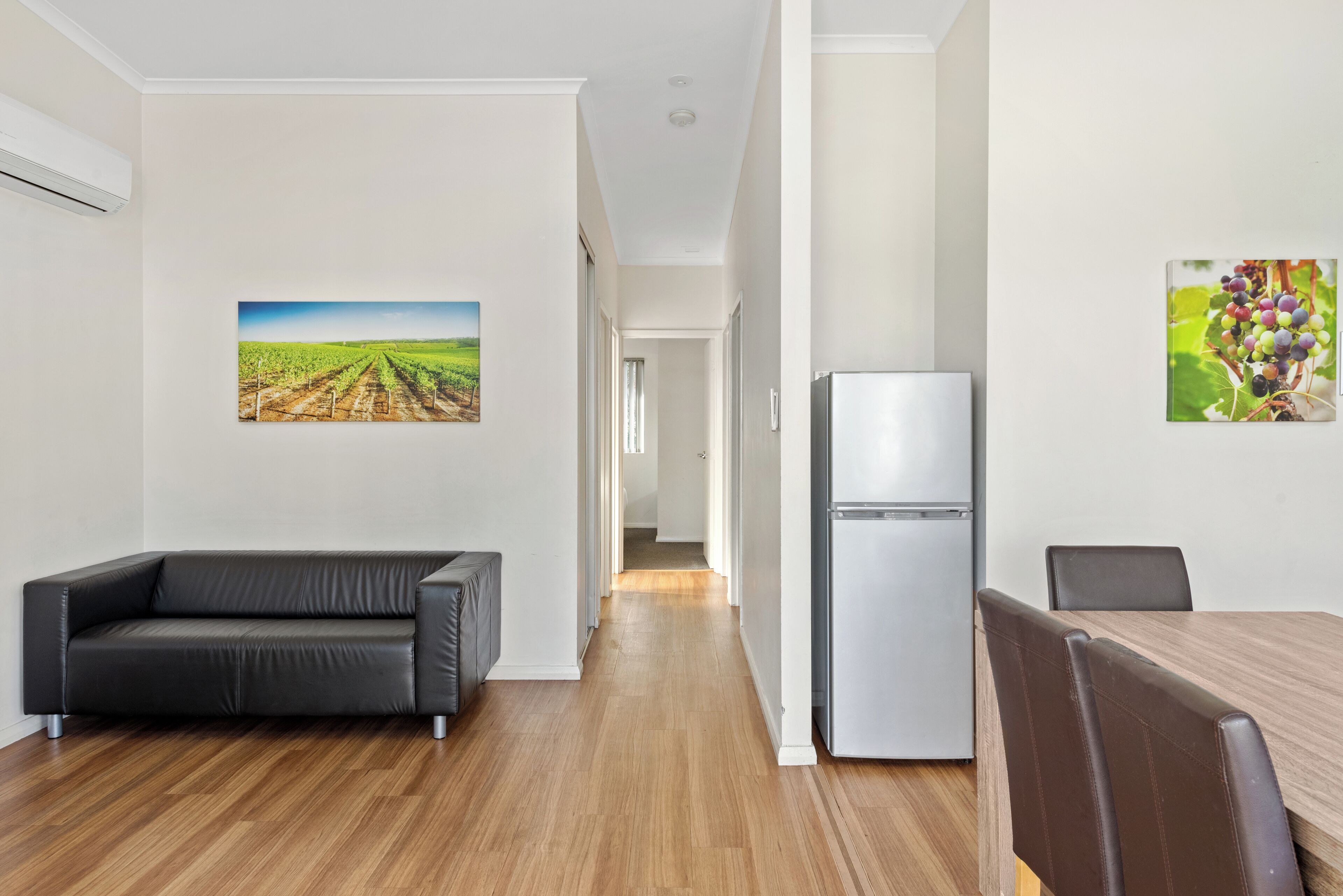 A modern kitchen with a refrigerator and a dining table with chairs.
