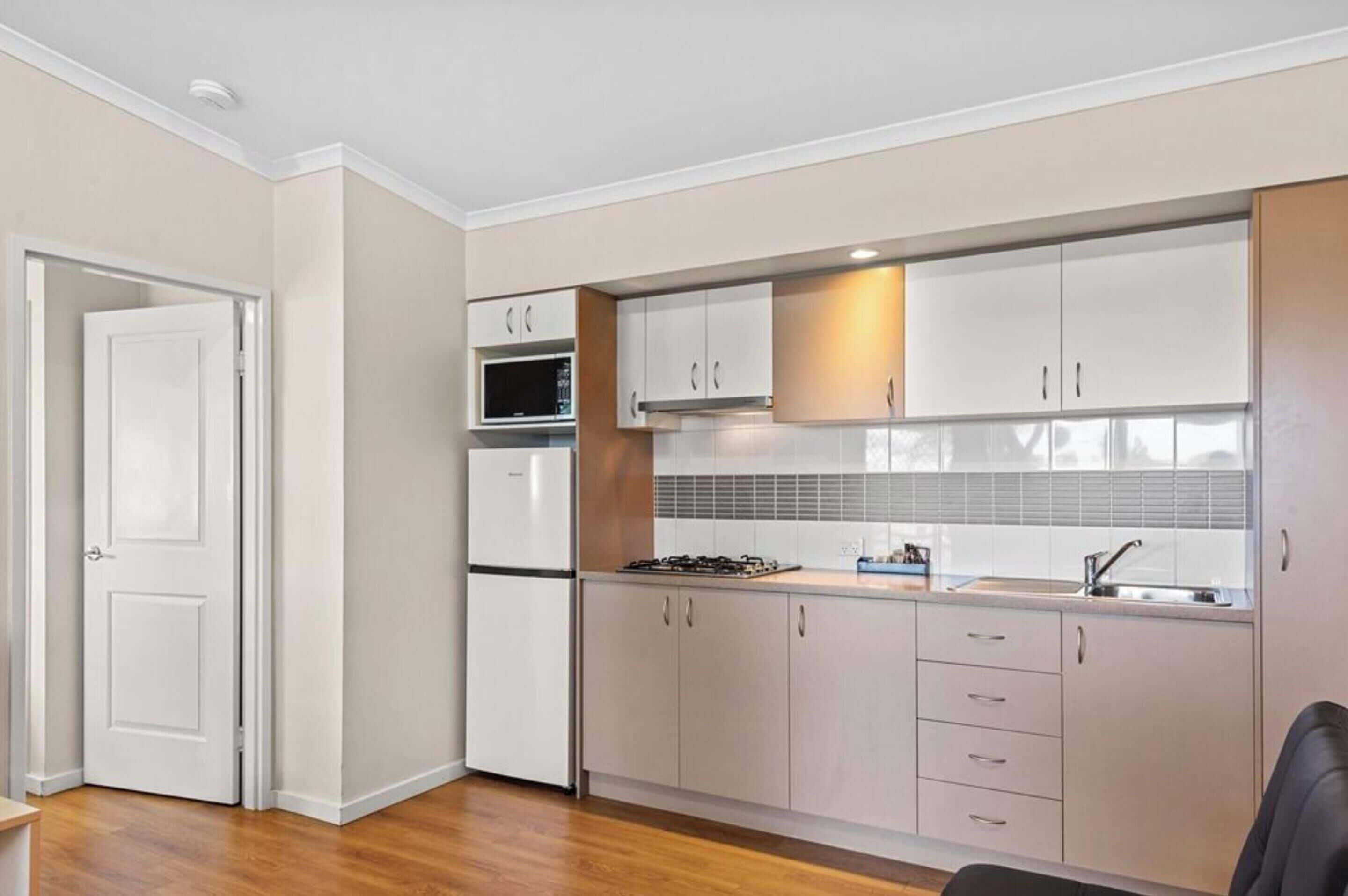 A modern kitchen with white cabinets, a built-in microwave, and a gas stove.