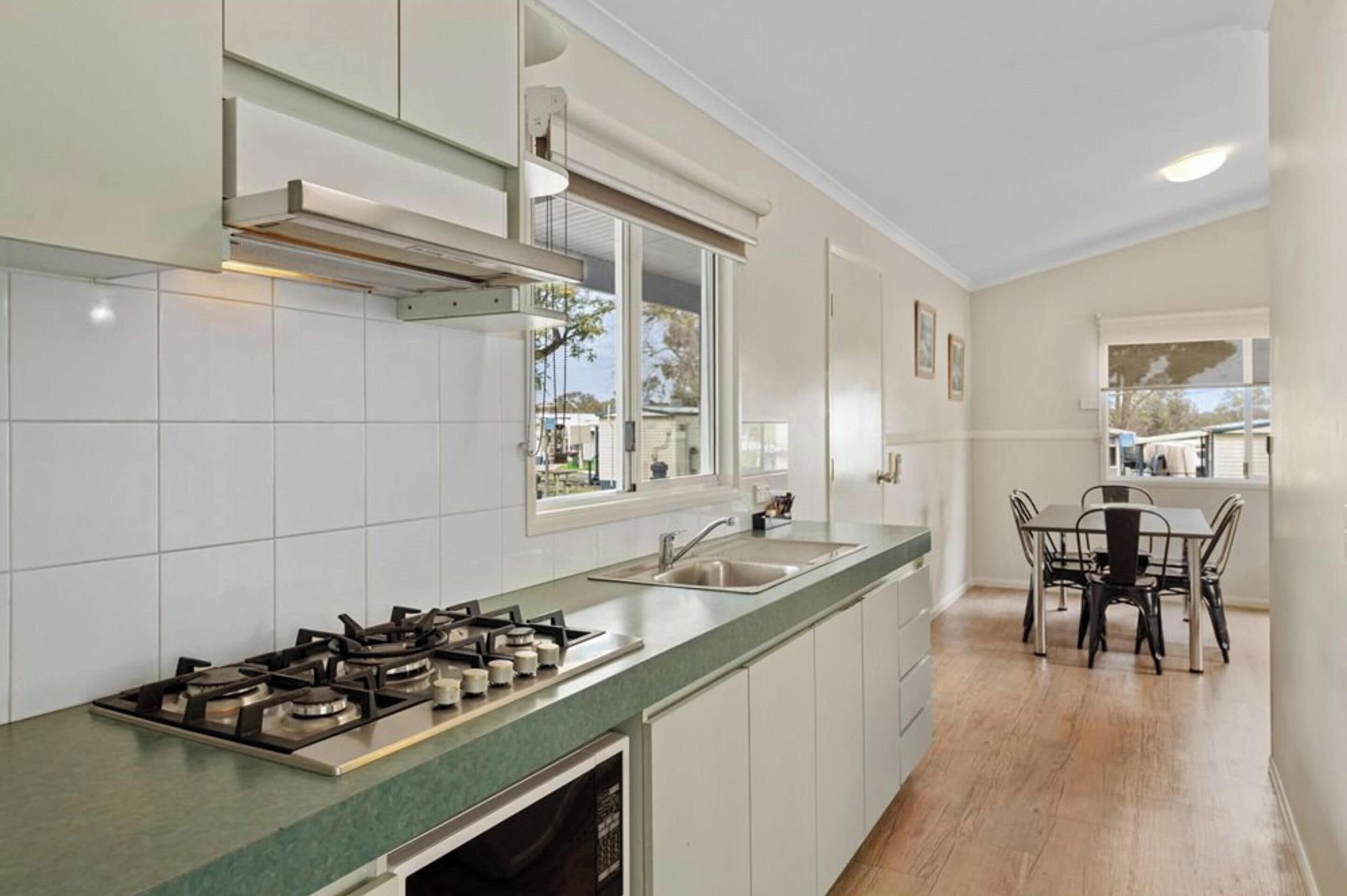 A modern kitchen with white cabinets, a green countertop, a gas stove, and a window overlooking the outdoors.
