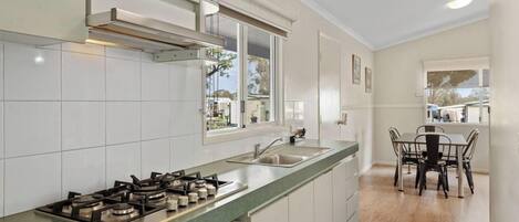A modern kitchen with white cabinets, a green countertop, a gas stove, and a window overlooking the outdoors.