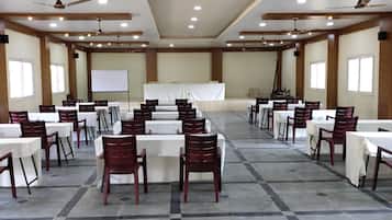 A conference room with multiple tables and chairs, a whiteboard, and a stage.