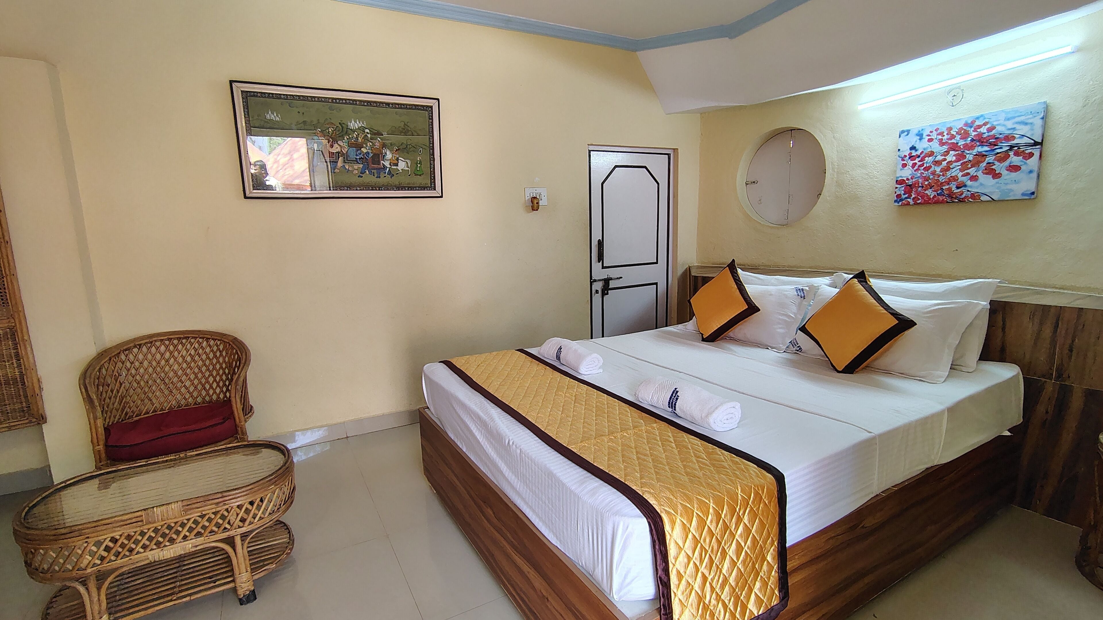 Una habitación de hotel con una cama, una silla, un cuadro y una puerta.