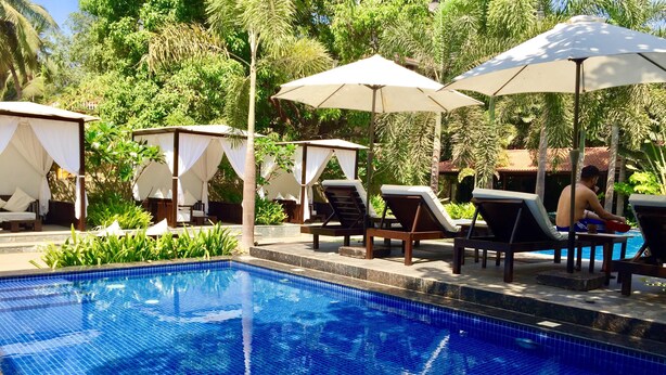 A pool area with tiled flooring, lounge chairs, umbrellas, and a small pool. - SinQ Beach Resort (Calangute)
