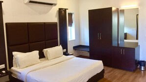 A hotel room with a large bed, a wardrobe, a mirror, and an air conditioning unit. - SinQ Beach Resort (Calangute)
