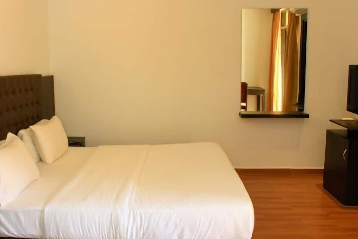 A neatly made bed with white linens, a wooden headboard, and a small bedside table.
