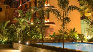 A multi-story hotel with balconies, a swimming pool, and tropical landscaping. - SinQ Beach Resort (Calangute)