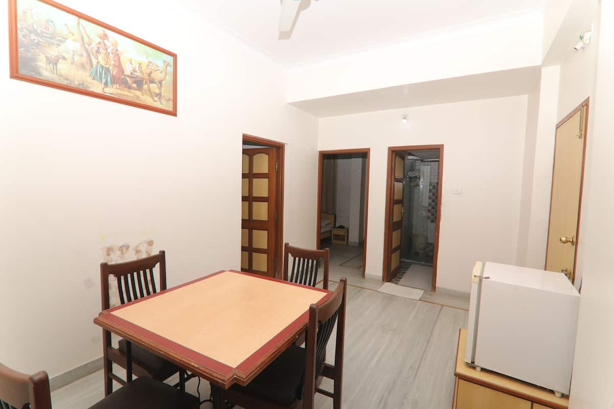 A dining area with a wooden table and chairs, a white refrigerator, and a framed picture on the wall.