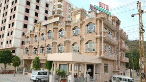 Un hotel de varios pisos con letrero de vista al jardín, balcones y pavimento a cuadros en la entrada.