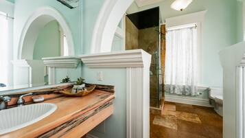 Une salle de bain avec un meuble-lavabo en marbre, un grand miroir, une douche et des toilettes.