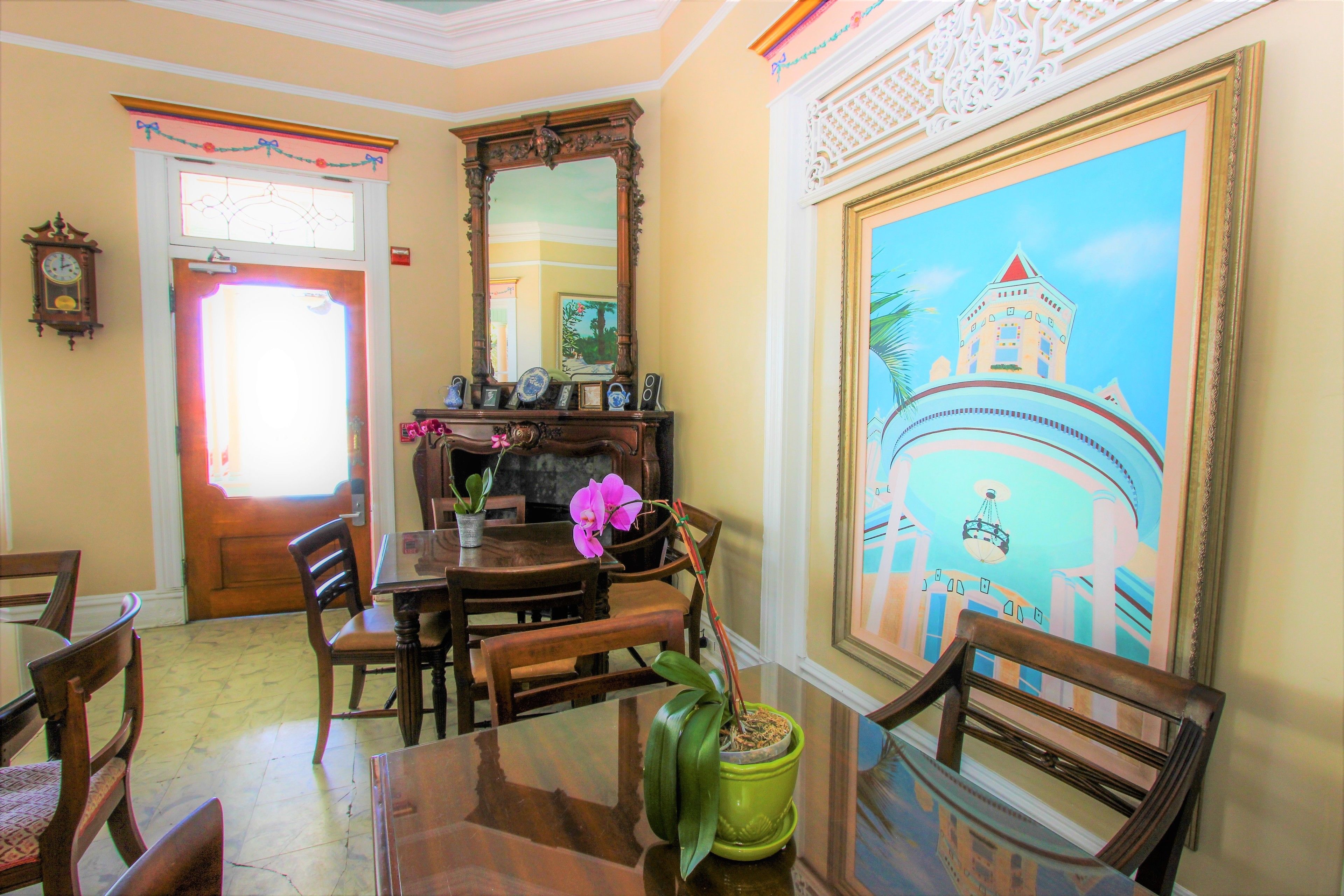 Comedor con muebles de madera, una planta en maceta verde y un cuadro grande con la imagen de un edificio.