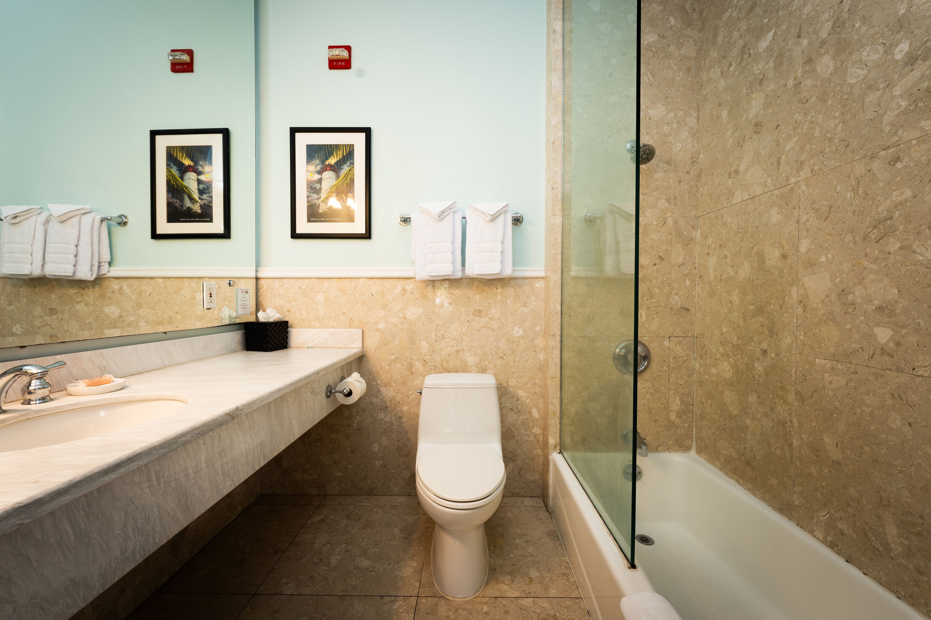 A bathroom with a marble sink, a toilet, and a glass-enclosed shower.