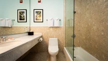 A bathroom with a marble sink, a toilet, and a glass-enclosed shower.