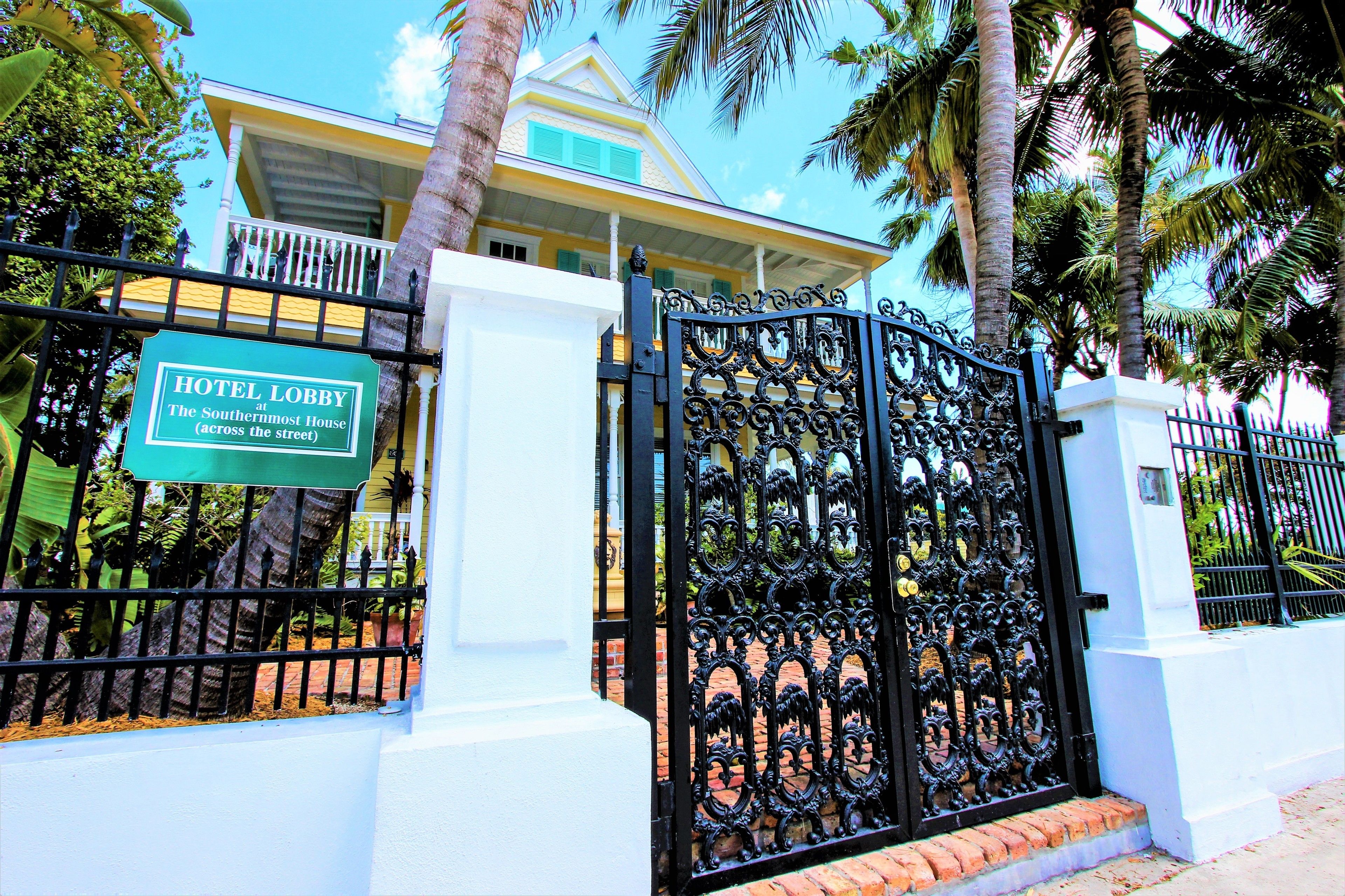 A gated entrance to a hotel lobby with a sign indicating it is the southernmost house across the street.